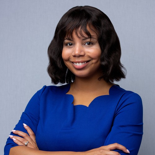 smiling woman in blue dress with arms crossed